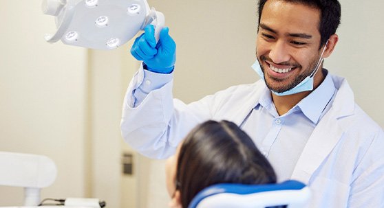 Dentist pulling light towards patient for examination