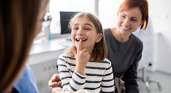 A dentist talking to a mother and daughter at a dental checkup
