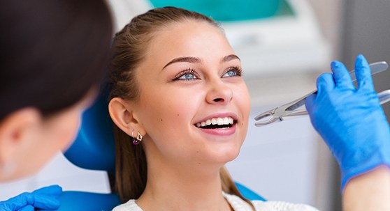 Woman in dental chair smiling about to have tooth extracted