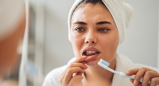 A woman looking at her gums in the mirror