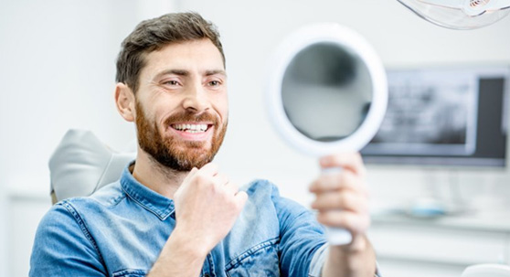 a patient checking his smile with a mirror