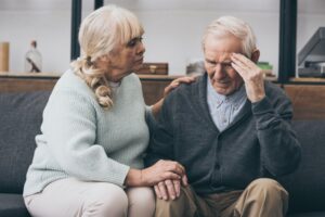 An elderly man and woman with man looking forgetful.