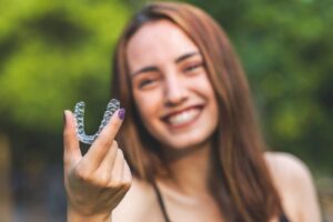 Woman smiling while getting ready to put in her Invisalign