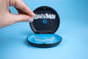a hand putting Invisalign trays in a case